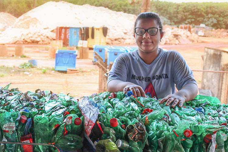 A foto mostra Miriam Silva Benvindo, cooperada da Cooprelp, apoiada em garrafas plásticas que serão destinadas à reciclagem.