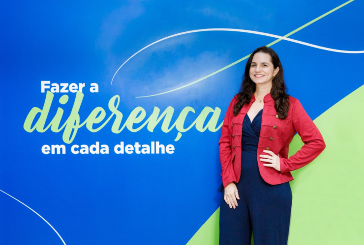 Pessoa posa diante de painel azul com a frase “Fazer a diferença em cada detalhe”