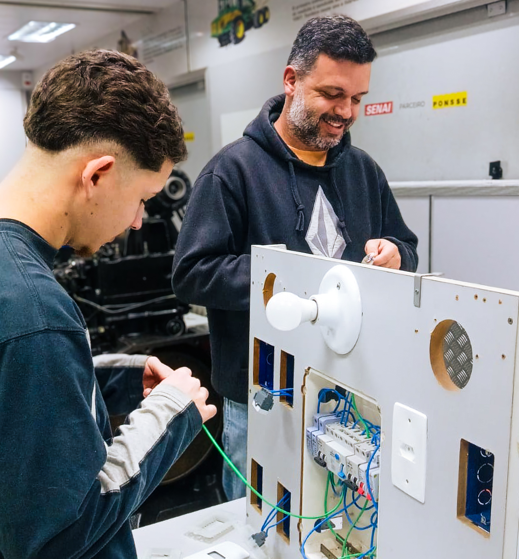 Participantes realizam atividade prática de instalações elétricas em bancada de treinamento técnico.