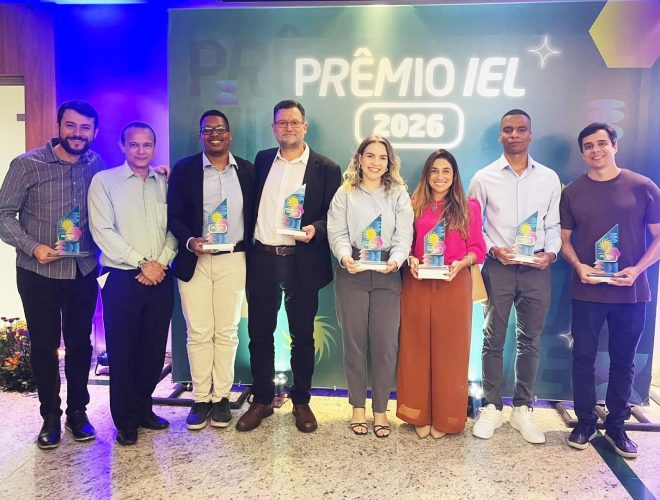 Equipe posa com troféus durante cerimônia do Prêmio IEL 2026 em frente ao painel oficial do evento.
