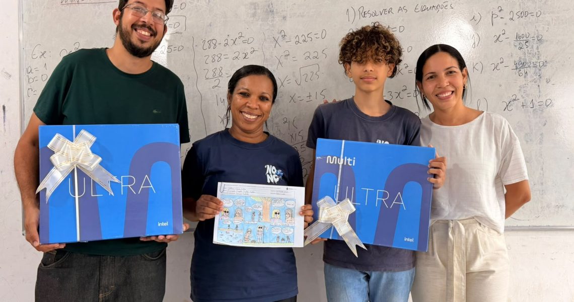 Estudante, profissionais da escola e representante exibem premiações e história em quadrinhos em sala de aula.