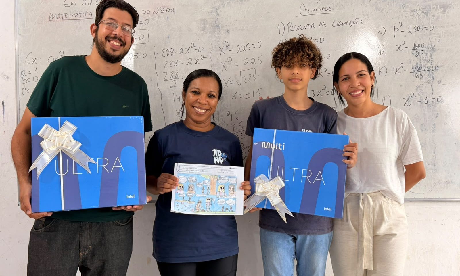 Estudante, profissionais da escola e representante exibem premiações e história em quadrinhos em sala de aula.