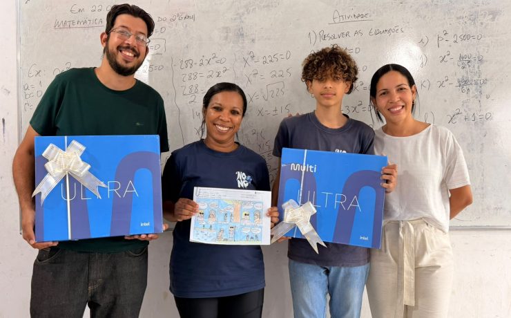 Estudante, profissionais da escola e representante exibem premiações e história em quadrinhos em sala de aula.