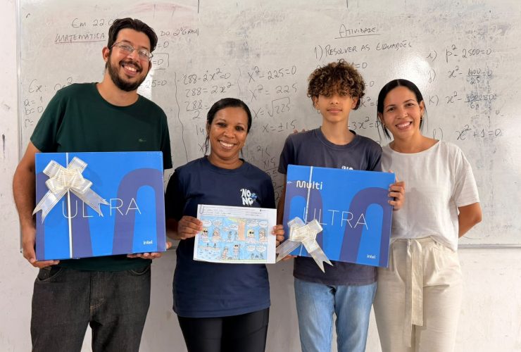 Estudante, profissionais da escola e representante exibem premiações e história em quadrinhos em sala de aula.